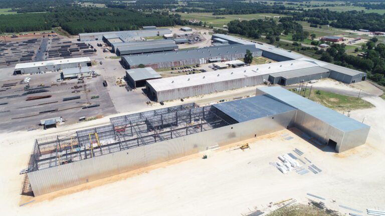 Completed aerial view of Vulcraft Texas grating facility featuring large industrial buildings with metal siding, crane runway systems, and equipment support structures engineered by CSD